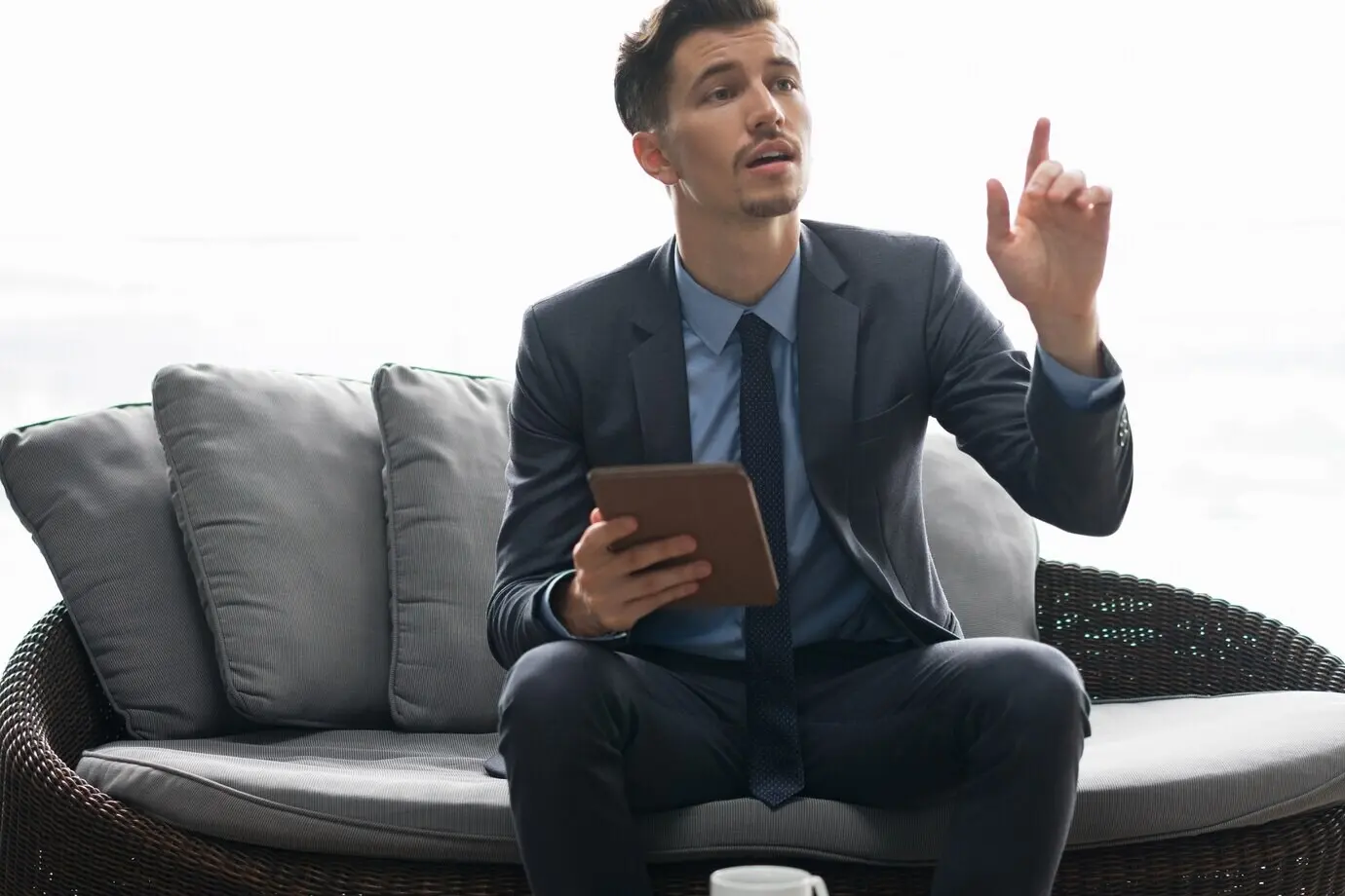 Успешный бизнесмен с планшетом зовёт официанта.